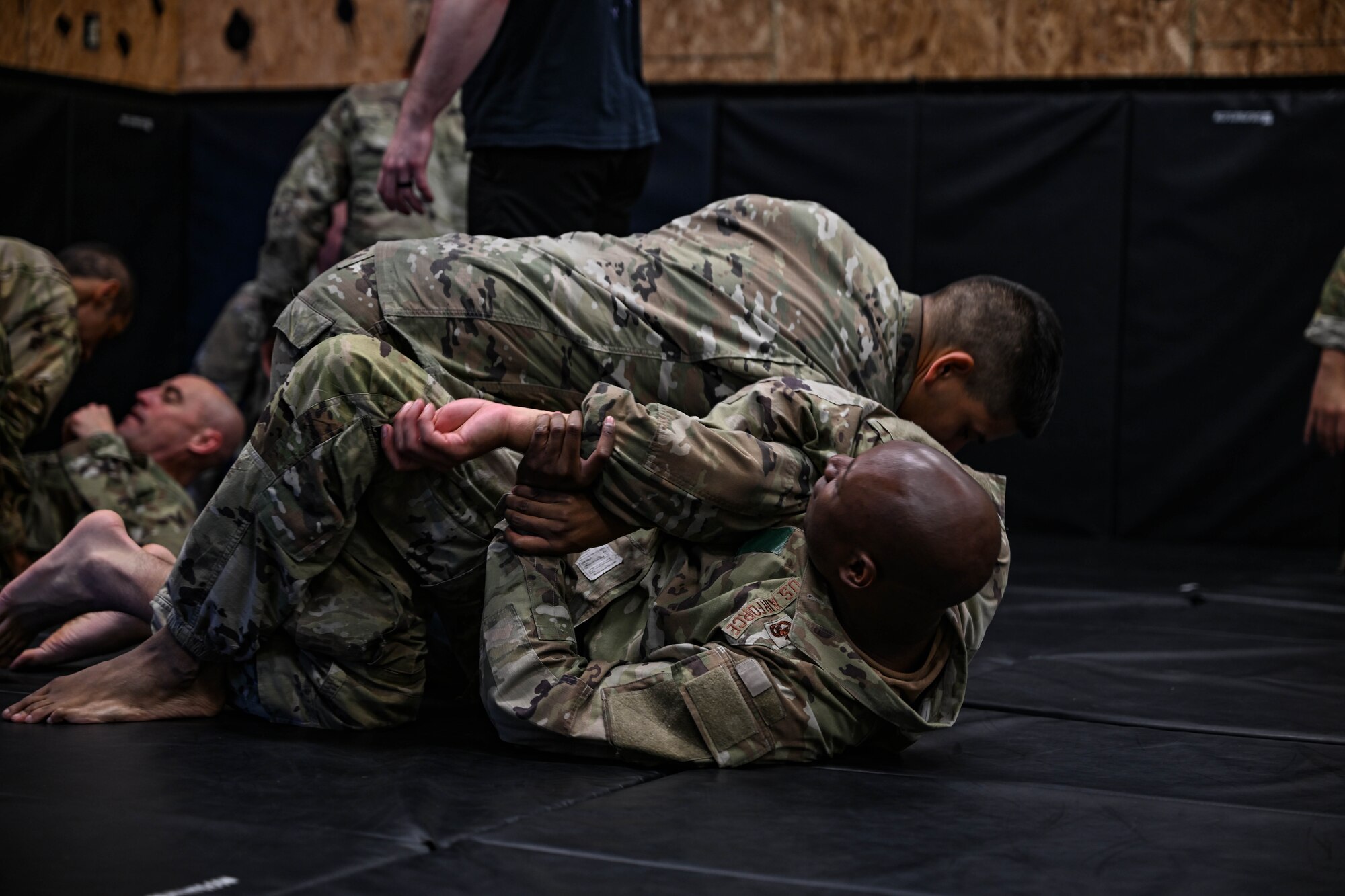 Two men in uniform wrestle on a mat.