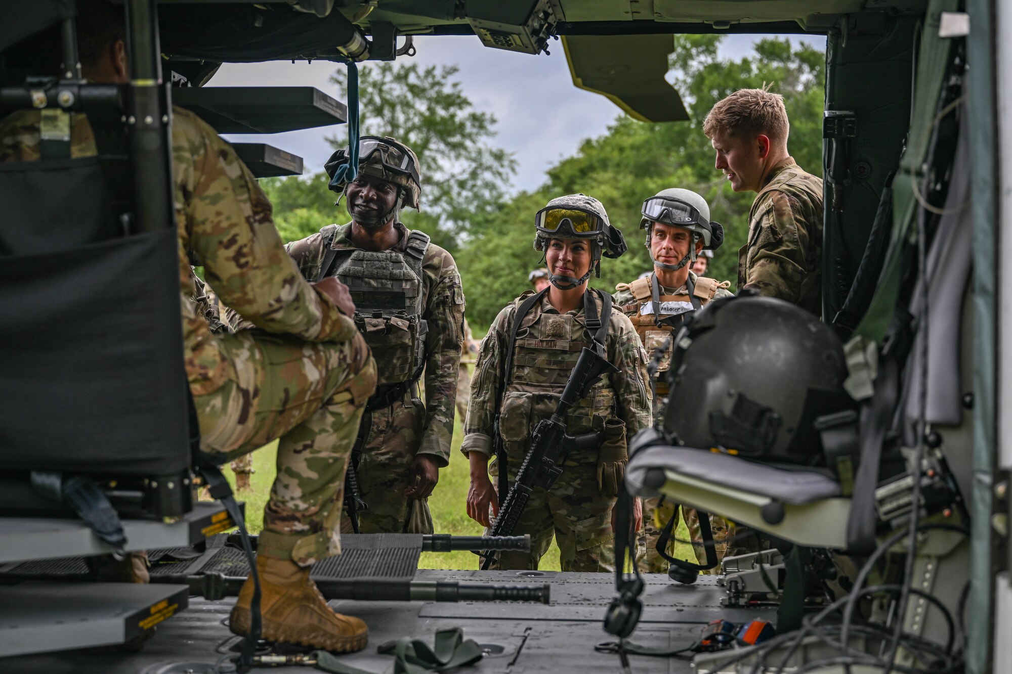 A group of people in uniform look inside a helicopter.