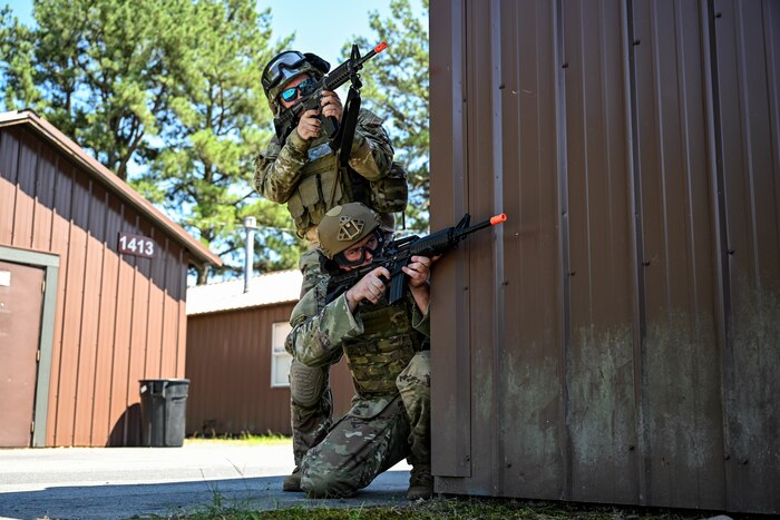 Two men in uniform aim airsoft weapons.