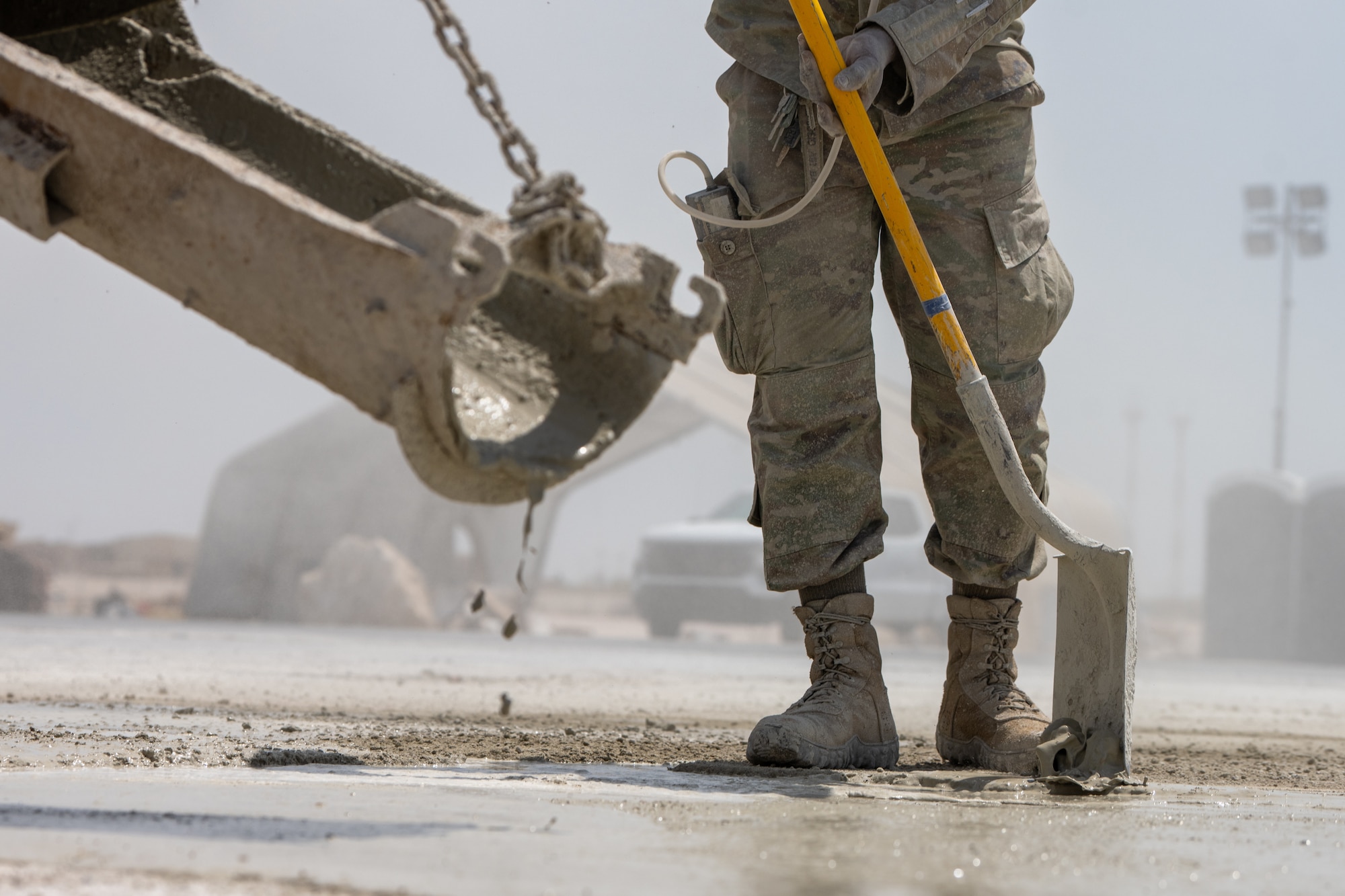 An Airman assigned to the 379th Expeditionary Civil Engineer Squadron uses a shovel to spread concrete mix during a Rapid Airfield Damage Repair exercise at an undisclosed location within the U.S. Central Command area of responsibility, June 12, 2024.
