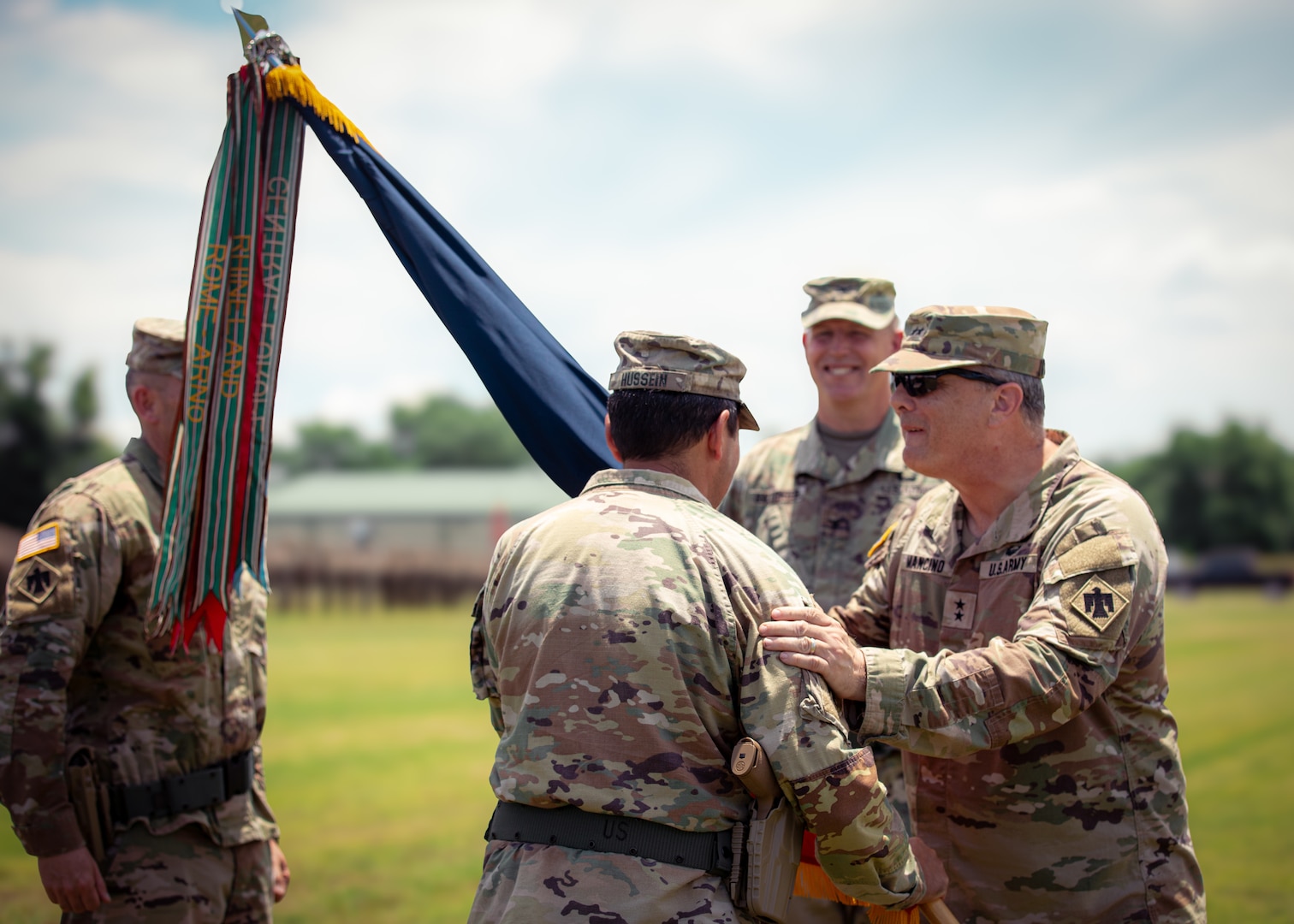 Maj. Gen. Thomas Mancino, adjutant general for Oklahoma, passes the unit colors to Col. Khalid Hussein, incoming commander of the 45th Infantry Brigade Combat Team, Oklahoma Army National Guard, during a change of command ceremony held at Camp Gruber Training Center near Braggs, Oklahoma, June 11, 2024. Command of the 45th IBCT passed from Col. Andrew Ballenger, who led the unit since 2022 through numerous deployments and training exercises. (Oklahoma National Guard photo by Cpl. Danielle Rayon)