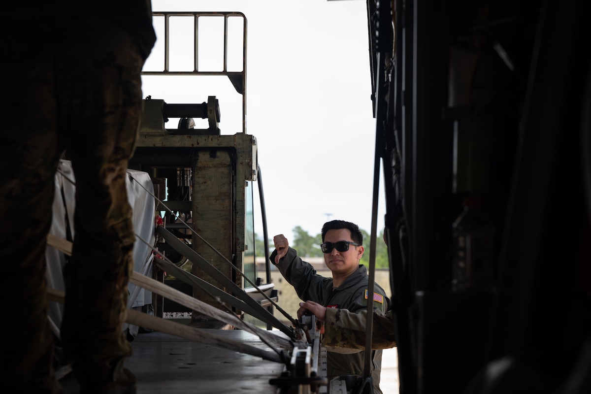 Airman directs the load of a cargo pallet onto a C-130J Super Hercules.