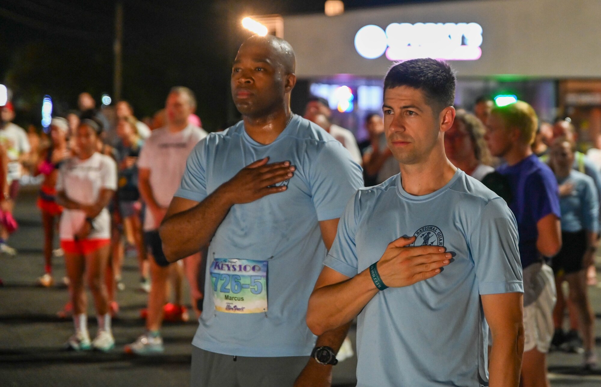 U.S. Air Force First  Sgt. Joshua R. Johnson and First Sgt. Marcus Boykin both place their hands over their hearts during the singing of  the national anthem.