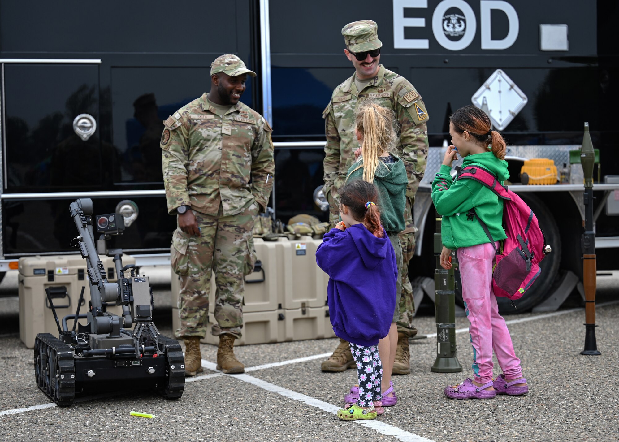 Two men in uniform interact with three children.