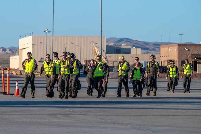 A large group of people walk on the flight line.