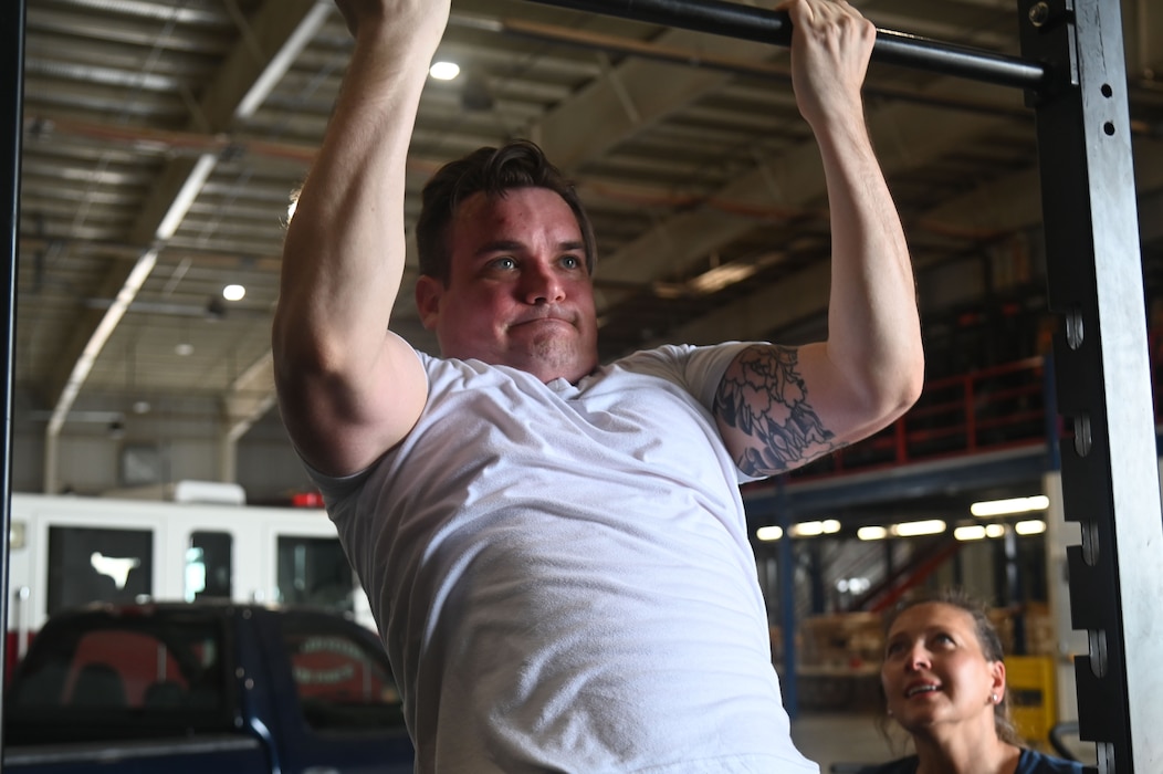 U.S. Air Force Tech. Sgt. Michael Swords, 312th Training Squadron instructor supervisor, is coached by Cheri Cotton, Operational Support Teams strength and conditioning coach, exercise physiologist, and nutritionist, while doing chin-ups at the Louis F. Garland Department of Defense Fire Academy, Goodfellow Air Force Base, Texas, March 30, 2024. The OST medical provider gave feedback and provided healthier alternatives to daily routine choices. (U.S. Air Force photo by Airman 1st Class James Salellas)