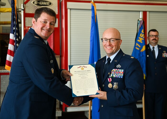 U.S. Air Force Col. Timothy Dalby, 17th Mission Support Group commander, left, presents a Meritorious Service Medal to Lt. Col. Joshua Carroll, 17th Civil Engineering Squadron outgoing commander, right, during the change of command ceremony at the Goodfellow Fire Department, Goodfellow Air Force Base, Texas, June 13, 2024. Carroll was the commander of the 17th CES from June 2022 until June 2024. (U.S. Air Force photo by Airman 1st Class Evelyn J. D’Errico)
