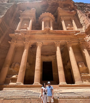 A man and a woman standing in front of an ancient building.