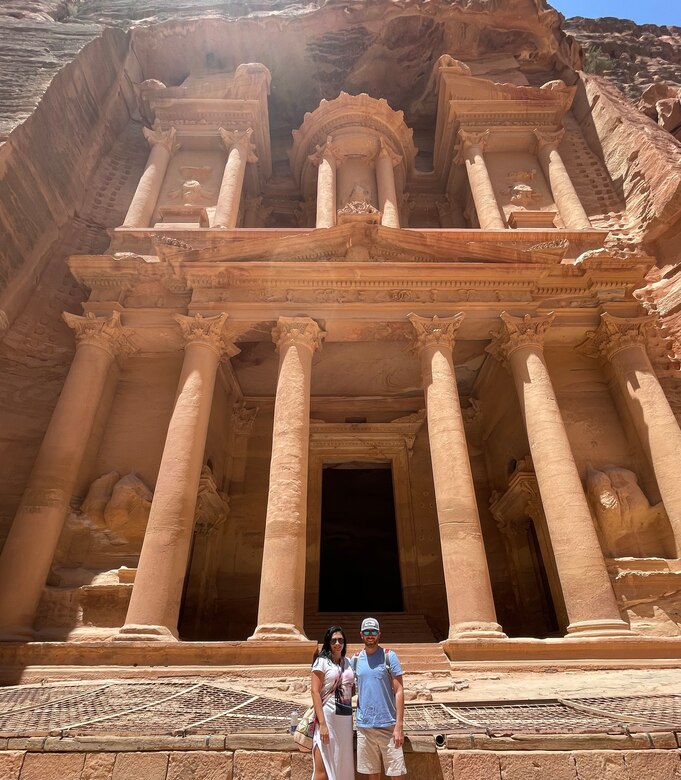 A man and a woman standing in front of an ancient building.