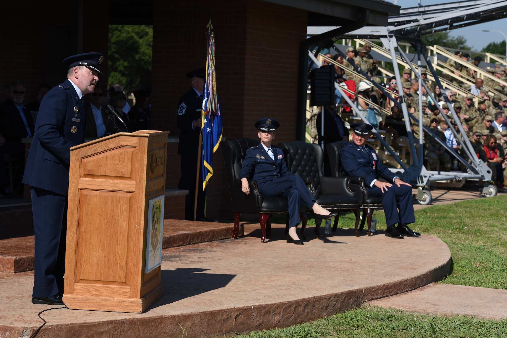 An officer speaks at a podium while two more officers watch