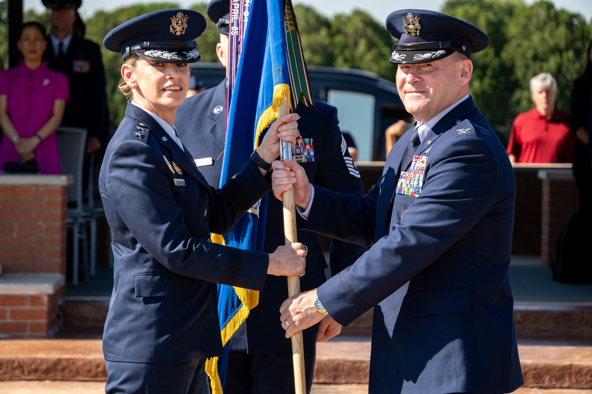 Two Airmen in uniform hold a guidon