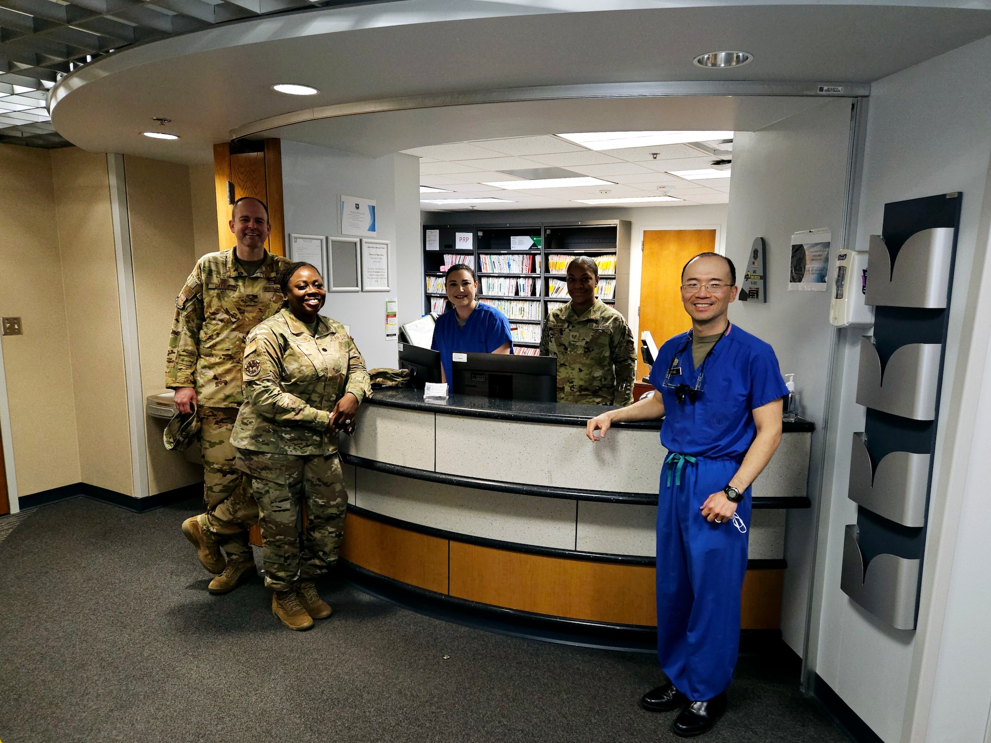 Service members in uniform and scrubs pose for a photo at the dental clinic.