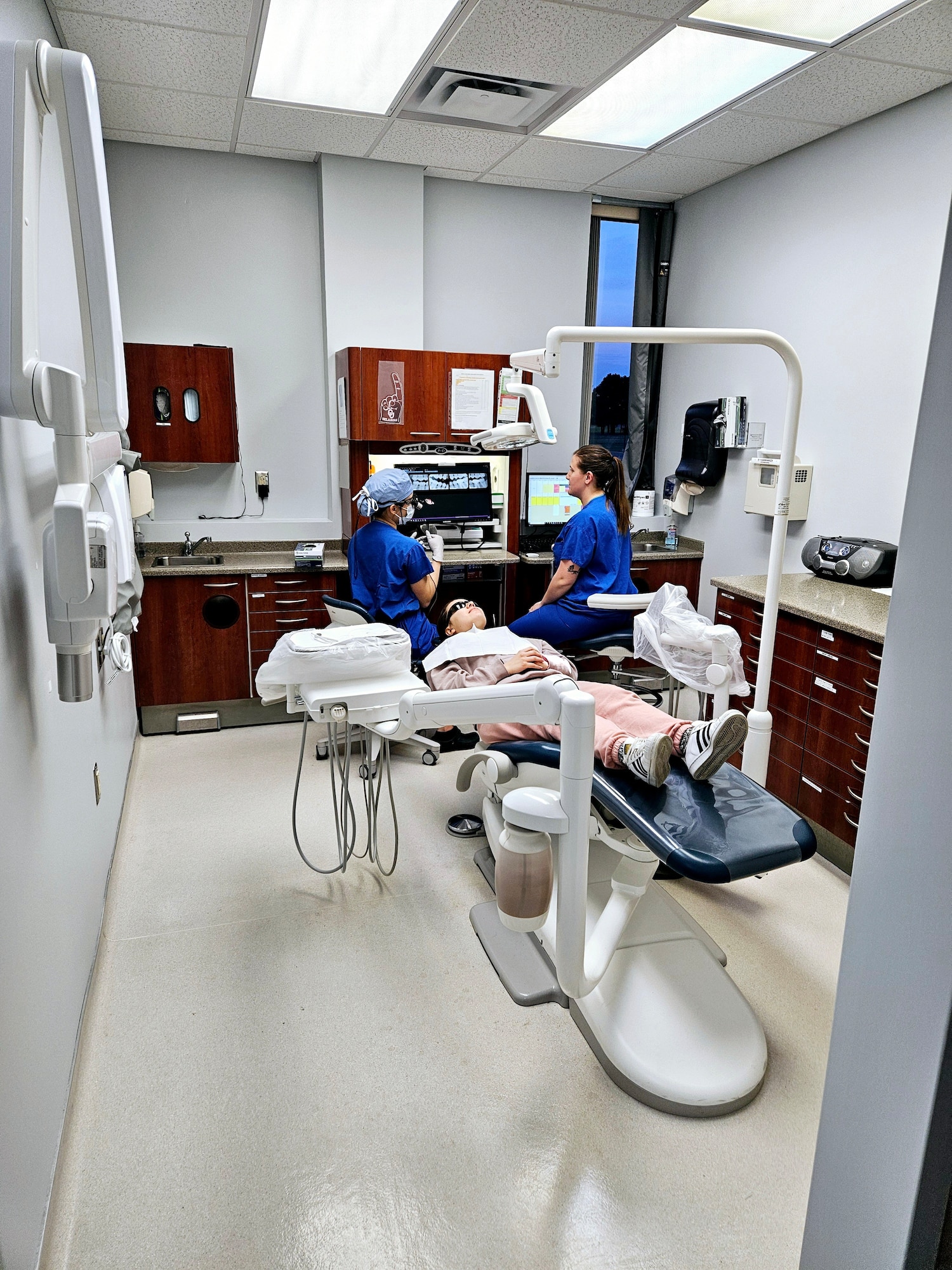 Two dental workers provide dental care to a patient.