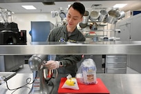 Tech. Sgt. Lang Xiao, flight attendant, D.C. Air National Guard, preps a five course meal prior to a Congressional transport at Joint Base Andrews, Md., May 19, 2024. The former communication designer embraces the challenge each new mission brings as a D.C. Air National Guard flight attendant to include a strong a desire for international travel.