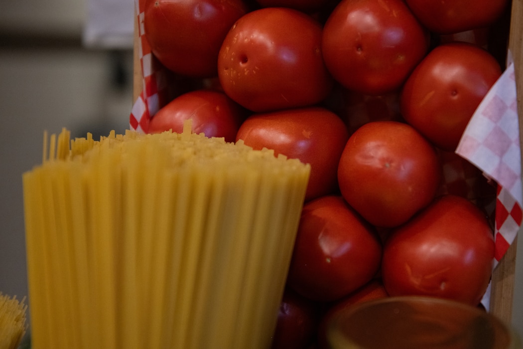 Tomatoes and spaghetti rest on counter.