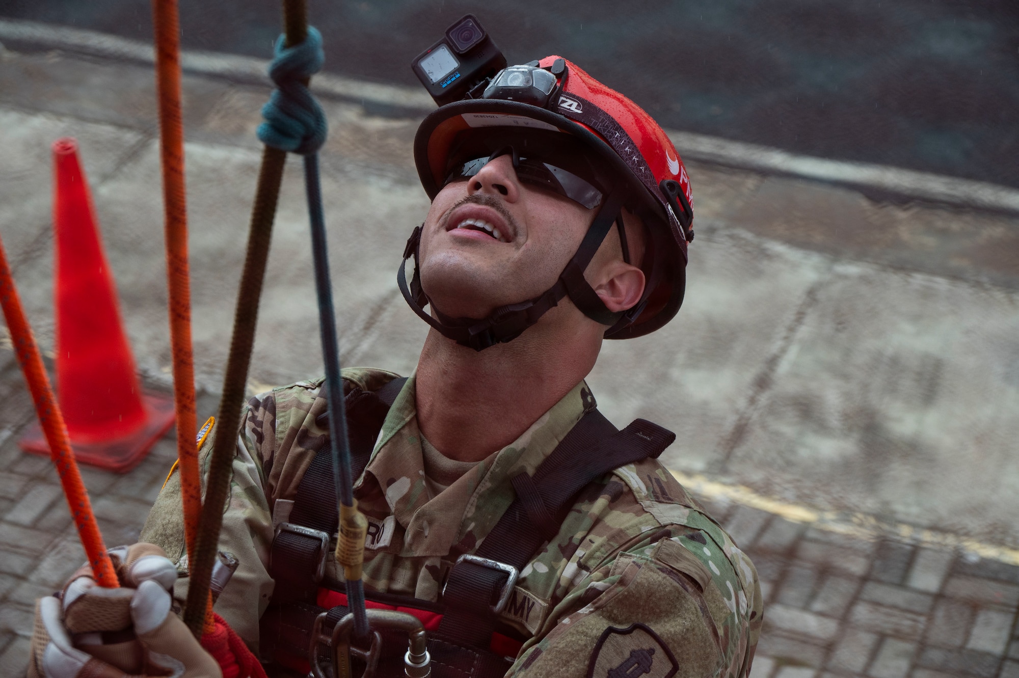 A photo of a person in a repelling system looking up.