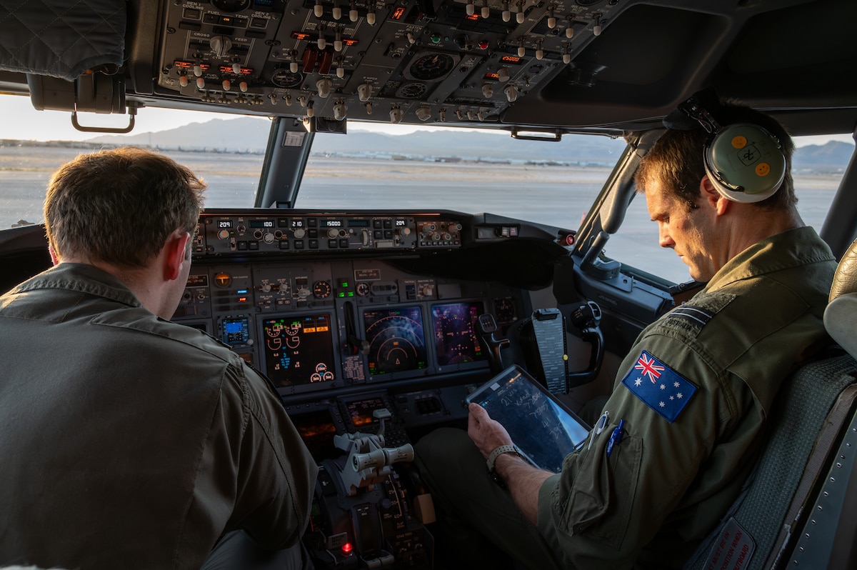 Two pilots sit in the cockpit of an E-7A Wedgetail aircraft.