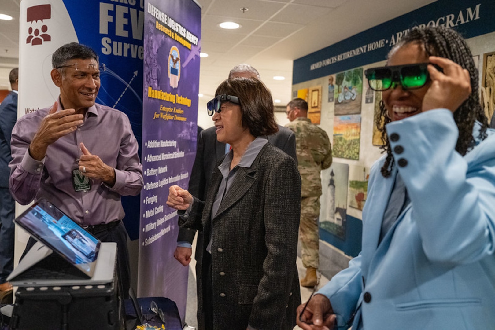 A person speaks as two others wear technical glasses in front of a floor display.