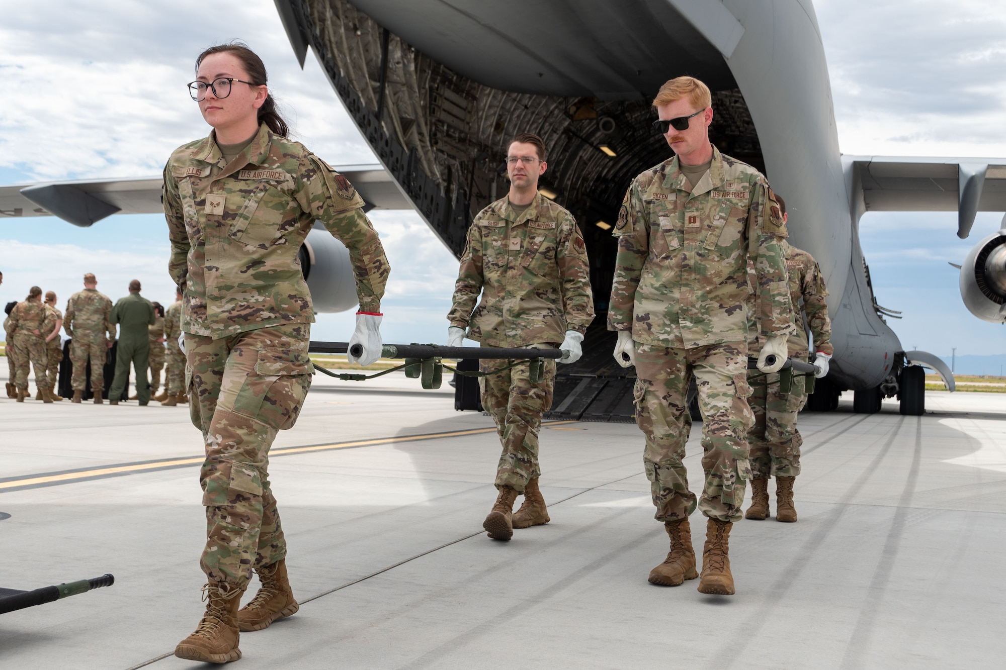U.S. Air Force Airman carry a litter out of a plane.
