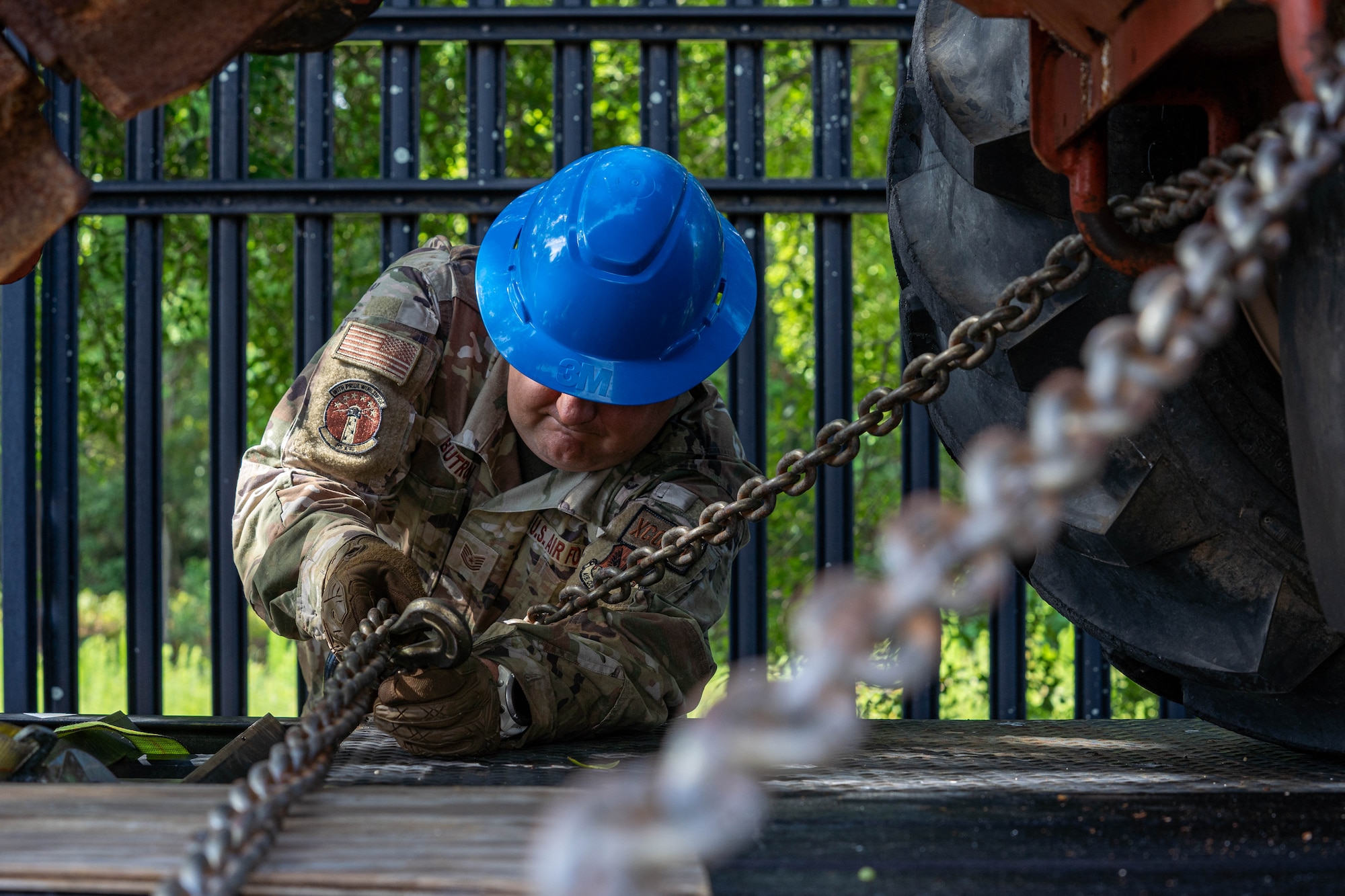 U.S. Air Force Tech. Sgt. Garret Butron, 85th Engineering Installation Squadron cable antennae maintenance technician, secures a bucket truck with a chain at the 85th EIS, Mississippi, May 21, 2024.