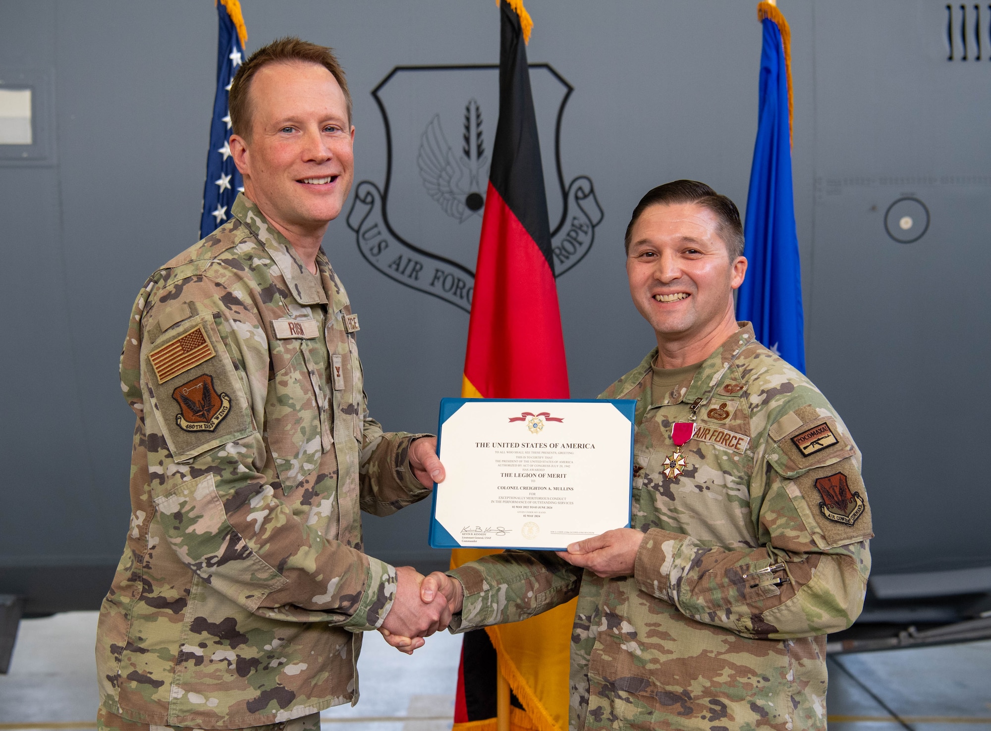 U.S. Air Force Col. Nathan Rusin, left, 480th Intelligence, Surveillance and Reconnaissance Wing commander, presents a decoration citation to Col. Creighton Mullins, right, 693rd Intelligence, Surveillance and Reconnaissance Group outgoing commander, during the 693rd ISRG change of command ceremony at Ramstein Air Base, Germany, June 6, 2024. The 693rd ISRG and its three subordinate squadrons conduct a variety of multi-intelligence operations, providing information to three combatant commands, combat forces and national leadership. (U.S. Air Force photo by Senior Airman Jared Lovett)