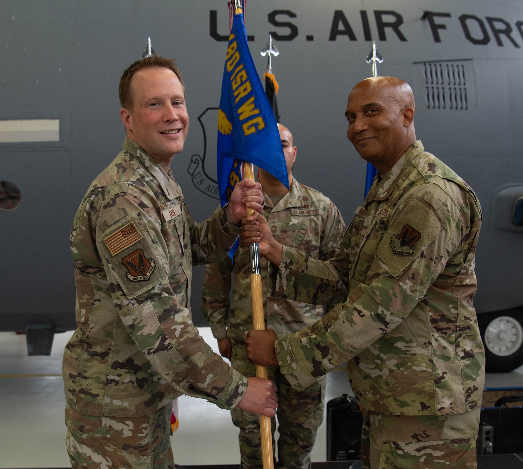 U.S. Air Force Col. Nathan Rusin, left, 480th Intelligence, Surveillance and Reconnaissance Wing commander, presents Col. Trevor Hollis, 693rd Intelligence, Surveillance and Reconnaissance Group incoming commander, with the 693rd ISRG guidon during the 693rd ISRG change of command ceremony at Ramstein Air Base, Germany, June 6, 2024. The 693rd ISRG and its three subordinate squadrons conduct a variety of multi-intelligence operations, providing information to three combatant commands, combat forces and national leadership. (U.S. Air Force photo by Senior Airman Jared Lovett)