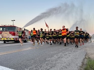 Soldiers from the 15th Signal Brigade run through a water spray provided by Fort Eisenhower Department of Emergency Services during a 5k run celebrating the 249th Birthday of the U.S. Army, June 14, 2024.