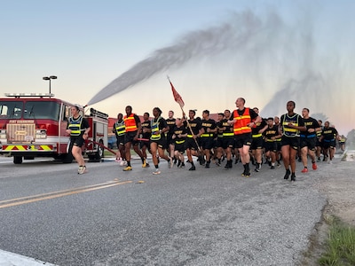Soldiers from the 15th Signal Brigade run through a water spray provided by Fort Eisenhower Department of Emergency Services during a 5k run celebrating the 249th Birthday of the U.S. Army, June 14, 2024.
