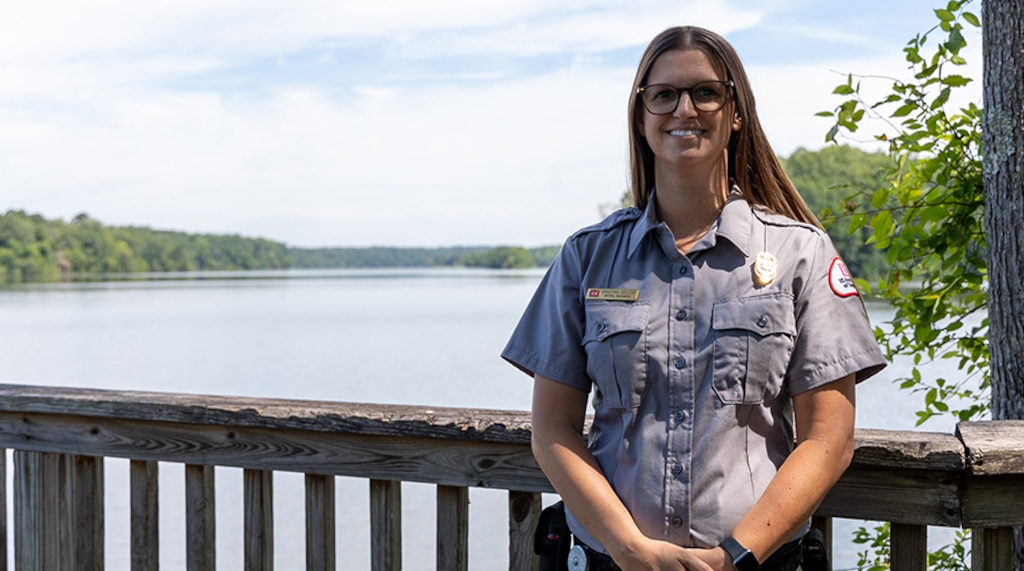 Woman standing on a pier in front of a lake.