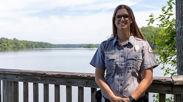 Woman standing on a pier in front of a lake.