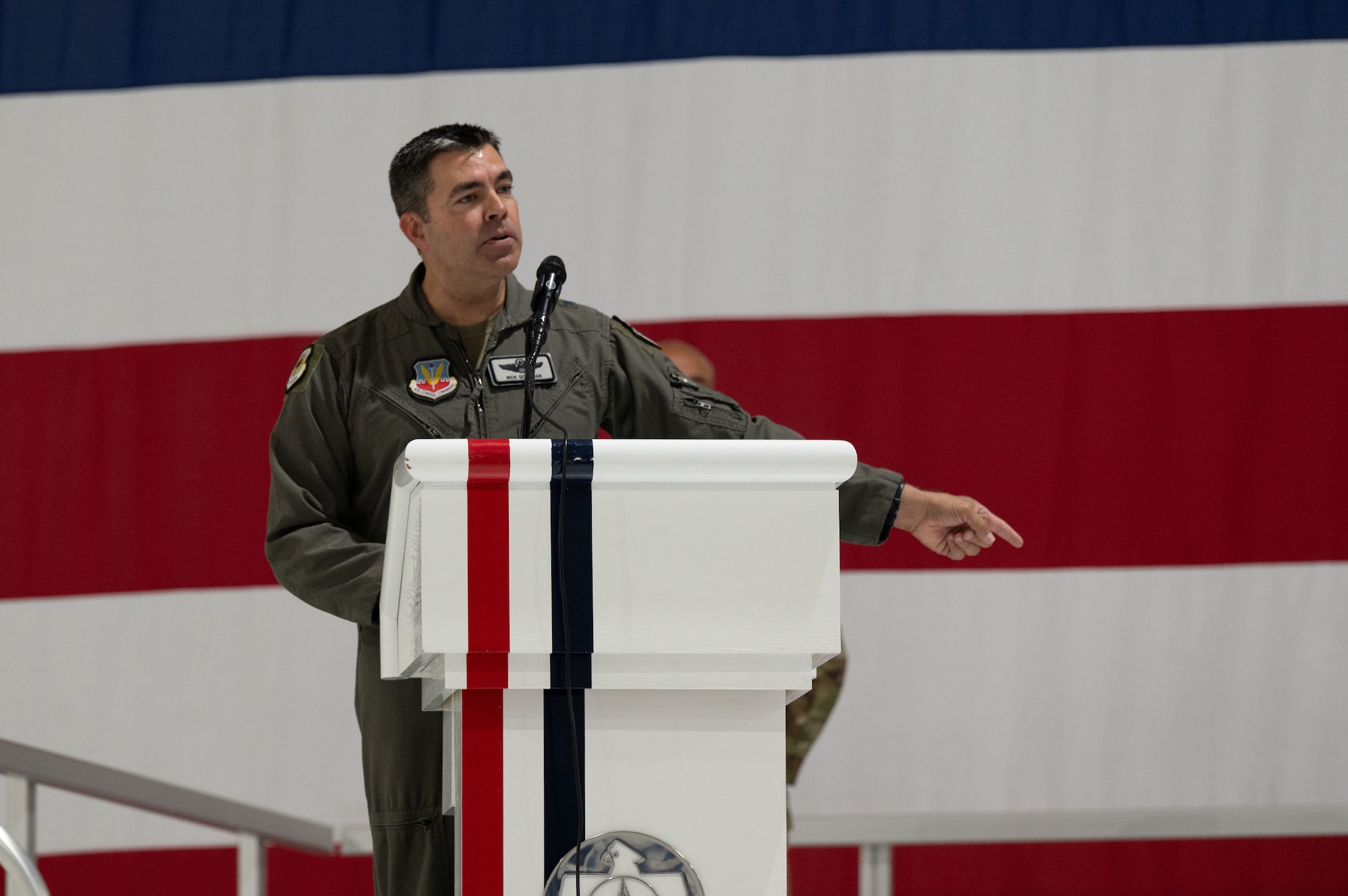 A man in uniform gestures from behind a podium.