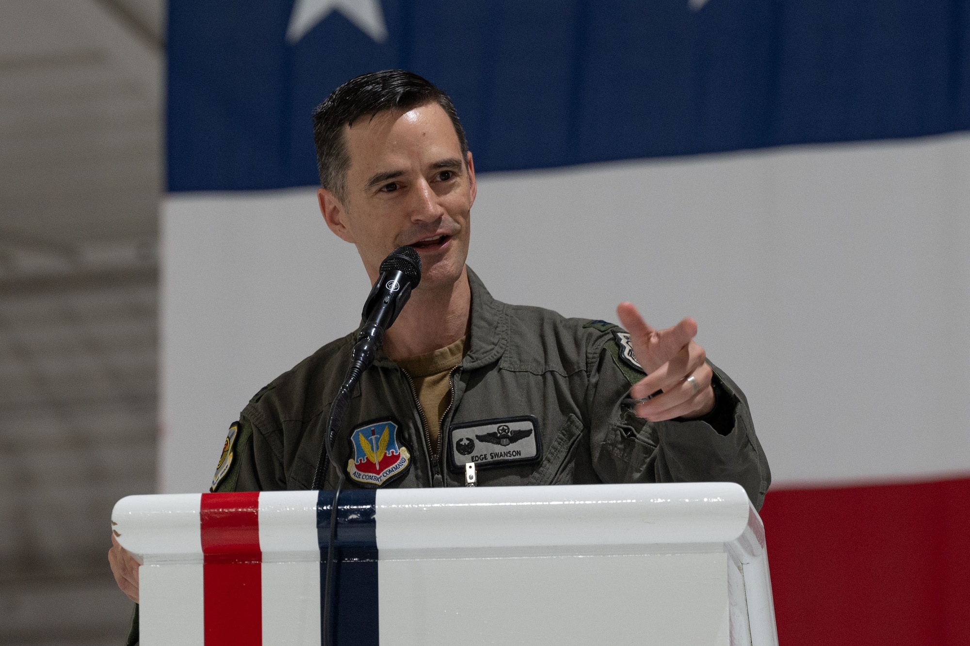 A man in uniform makes a gesture from behind a podium.