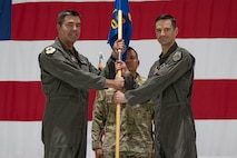 Two men hold a guidon onstage.