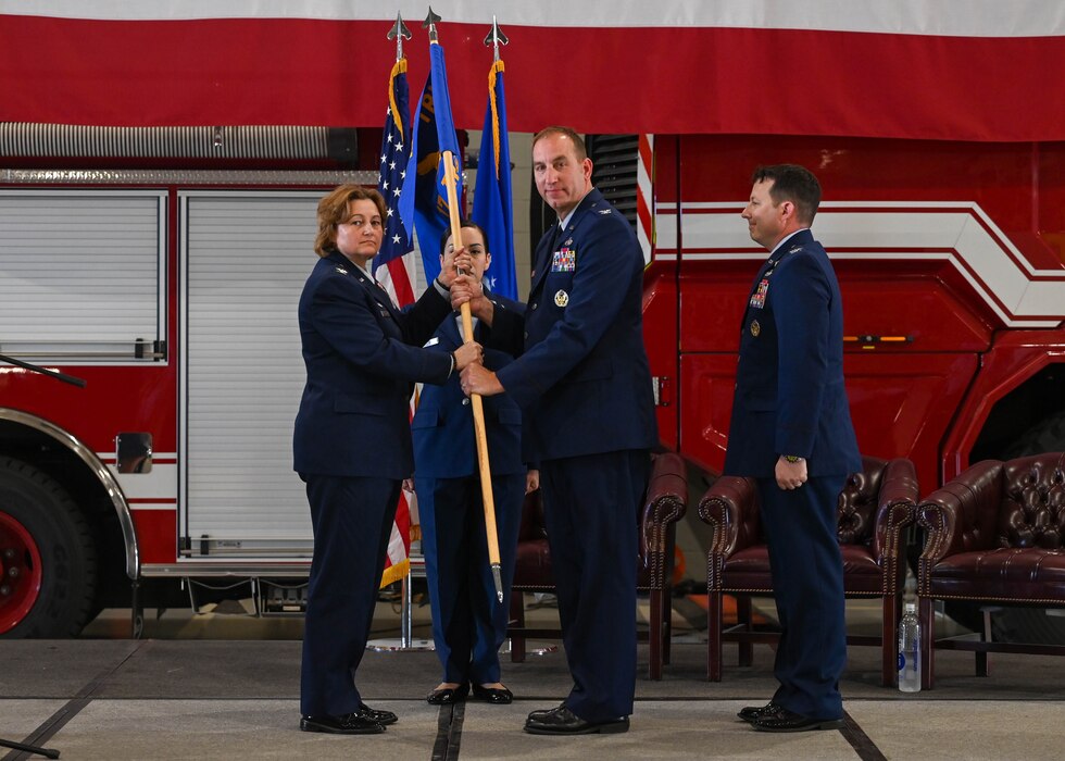 U.S. Air Force Col. Angelina Maguinness, 17th Training Wing commander, takes the guidon from Col. Jason Kulchar, outgoing 17th TRG commander, during the change of command ceremony at the Louis F. Garland Department of Defense Fire Academy, Goodfellow Air Force Base, Texas, June 14, 2024. Passing the guidon represents the transfer of leadership responsibilities to the next commander. (U.S. Air Force photo by Senior Airman Zach Heimbuch)