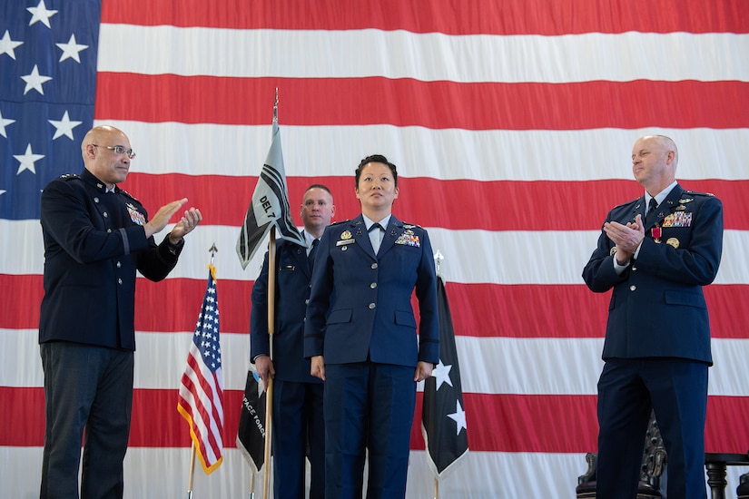 Service members stand in front of flags during a change of command ceremony.