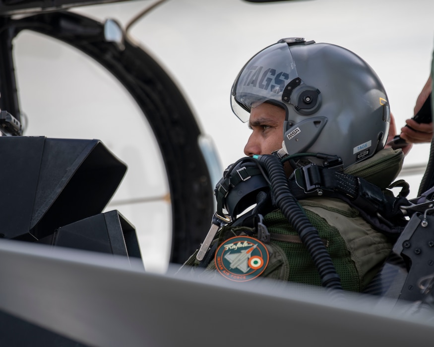 A pilot from the Indian Air Force sits in the cockpit of a Rafale aircraft with his helmet on in preparation for take-off.