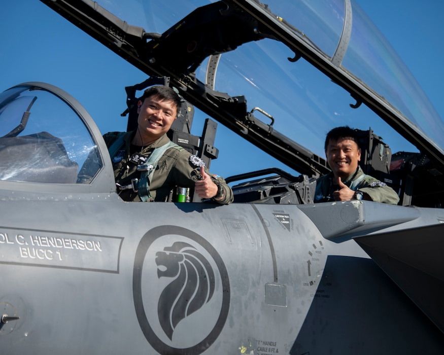 Two pilots from Republic of Singapore Air Force pose in the cockpit of an aircraft giving the thumbs up sign.