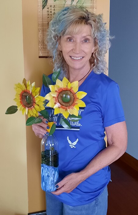 Chris Carl, a navigation project assistant at Cannelton Locks and Dam, poses for a photo with one of the pieces of art she created with recycled materials.