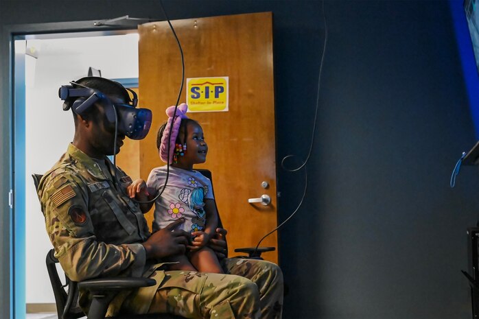 Airman and his daughter test out C-17 Globemaster III virtual reality simulator.
