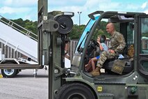 Airman and his son operate equipment during bring your family to work day.