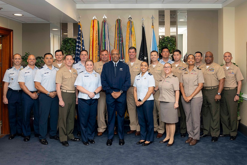 Service members in uniform stand side-by-side in a conference room.