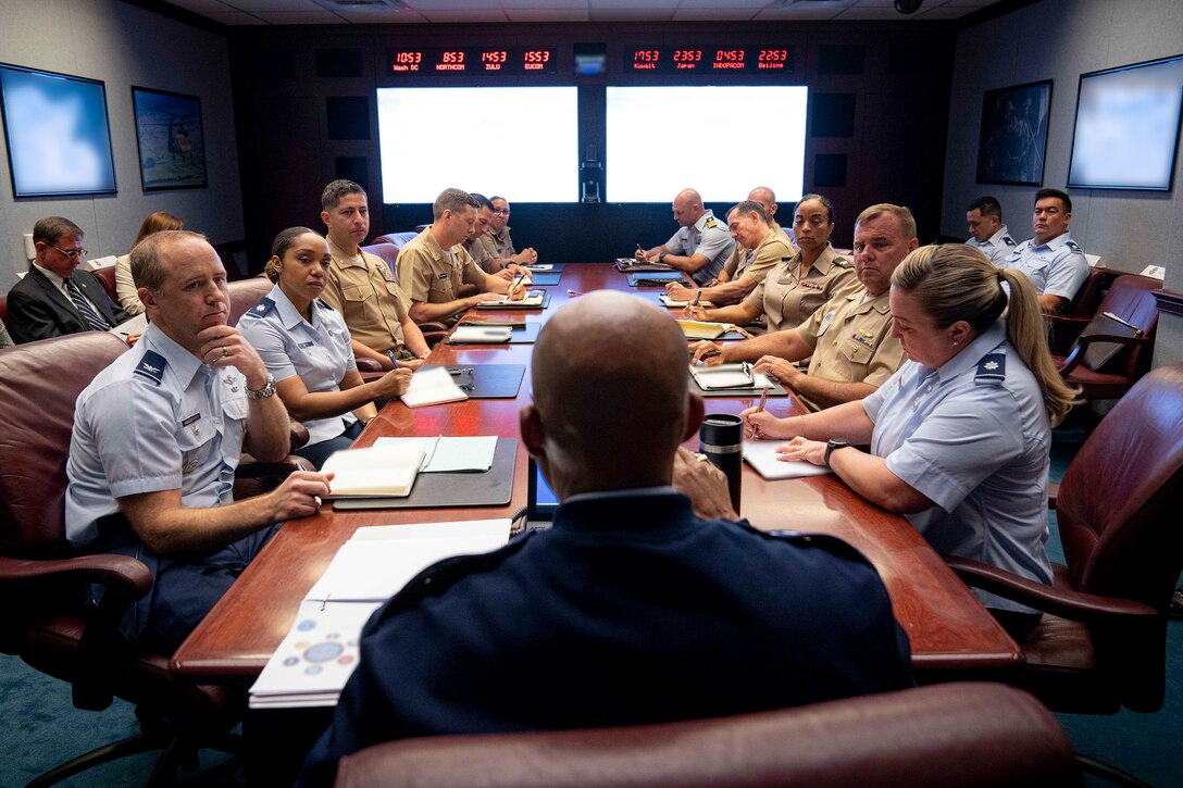 Service members in uniform are seated at a conference table.