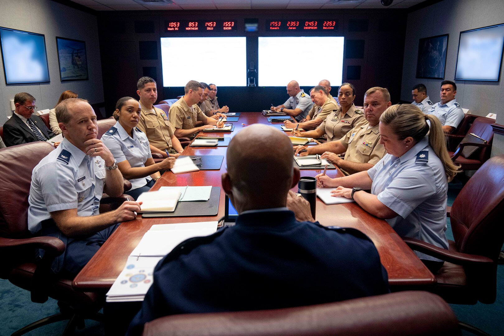Service members in uniform are seated at a conference table.