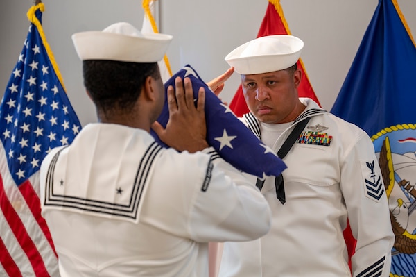 Hospital Corpsman 1st Class Raphael Claxton, the Bureau of Medicine and Surgery Senior Sailor of the Quarter, participates in a flag-folding ceremony during the 126th Hospital Corps birthday celebration at the Defense Health Headquarters in Falls Church, Virginia, June 17.