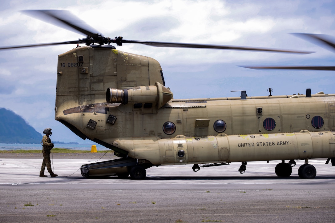U.S. Army Sgt. Cade Eastwood, a flight engineer with Bravo Company, 3rd Battalion, 25th Aviation Regiment, General Support Aviation Brigade, inspects a CH-47 Chinook in preparation for an external lift operations exercise at Marine Corps Air Station Kaneohe Bay, Marine Corps Base Hawaii, June 6, 2024. Marines and Soldiers collaborated in an external lift operations exercise, bolstering efficiency in airlifting oversized cargo while offering a distinctive cross-training opportunity. (U.S. Marine Corps photo by Lance Cpl. Carlos Daniel Chavez-Flores)