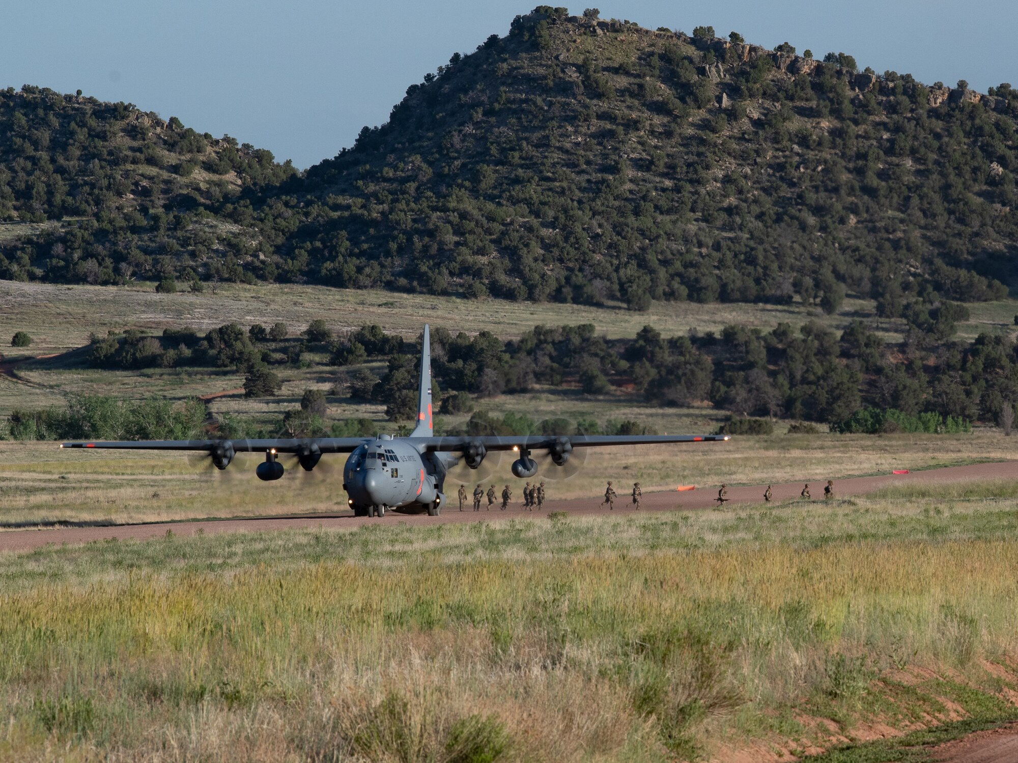 A line of military personnel prepare to enter the cargo bay of an aircraft.