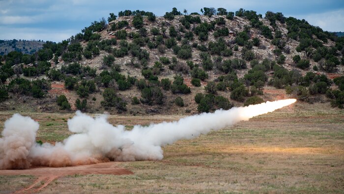 A rocket being fired in a field from a tactical truck.