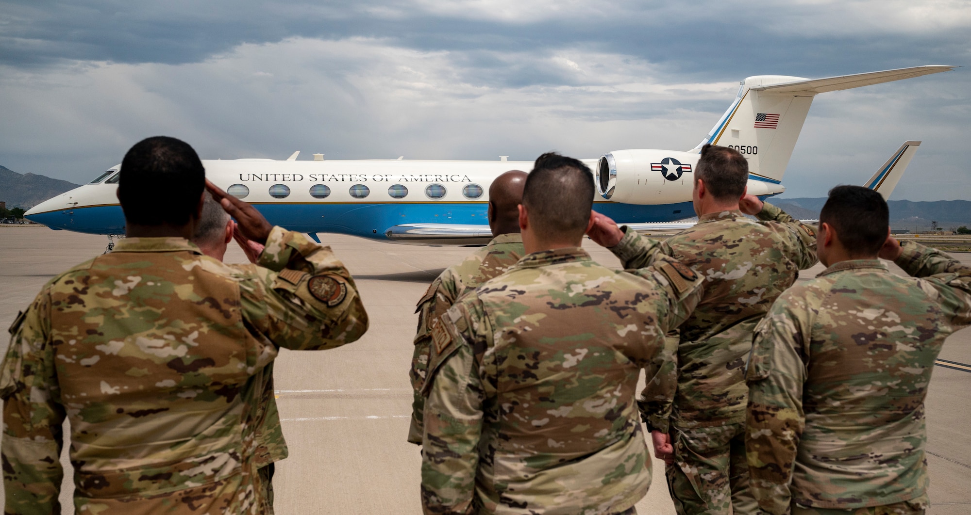 Service members salute plane.