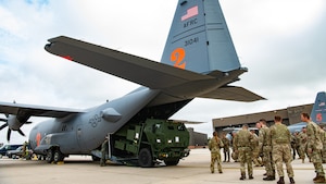 A tactical vehicle emerging from the cargo bay of a military aircraft.