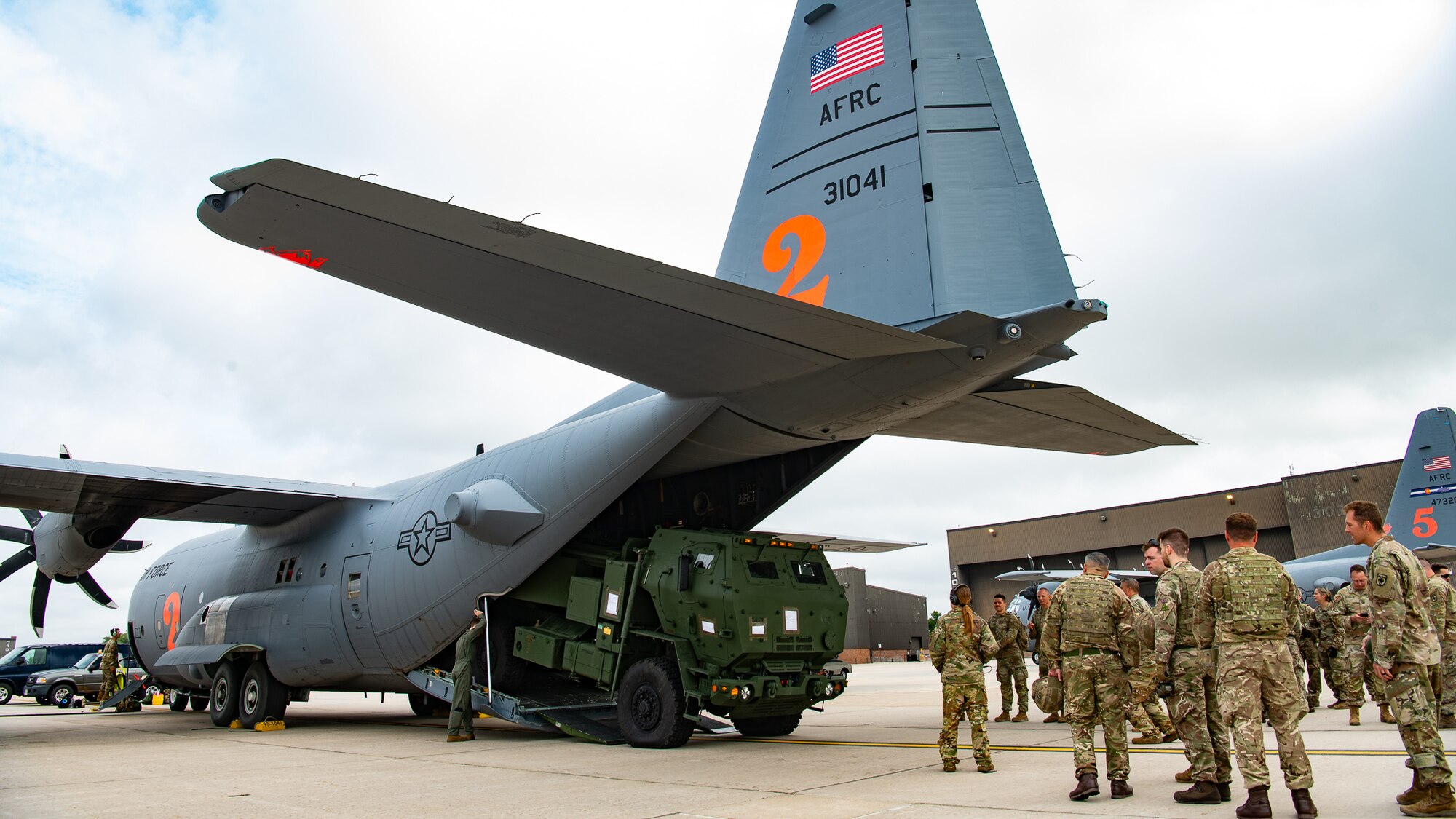 A tactical vehicle emerging from the cargo bay of a military aircraft.